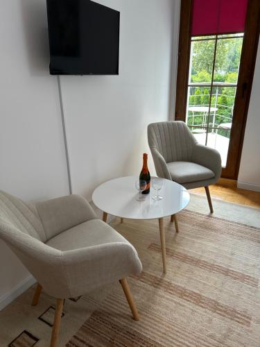 a living room with two chairs and a table with a bottle on it at Apartamenty przy uzdrowisku in Inowrocław