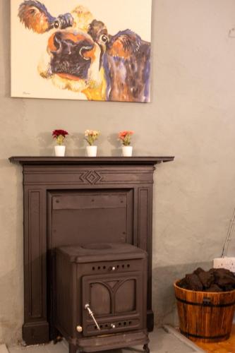 a fireplace with a picture of a cow on the wall at Moore's Cottage in Birr