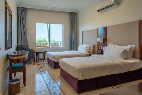 a hotel room with two beds and a window at Radwa Ramada Resort in Yanbu