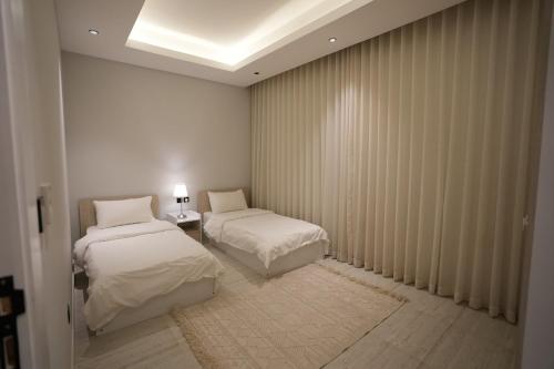リヤドにあるMajdiya 125 King Salman Dist 2BR Gym Poolのベッドルーム1室(ベッド2台付)、窓(カーテン付)