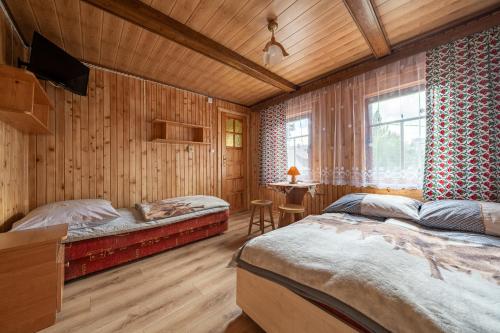 two beds in a room with wooden walls at U Chowańca in Murzasichle