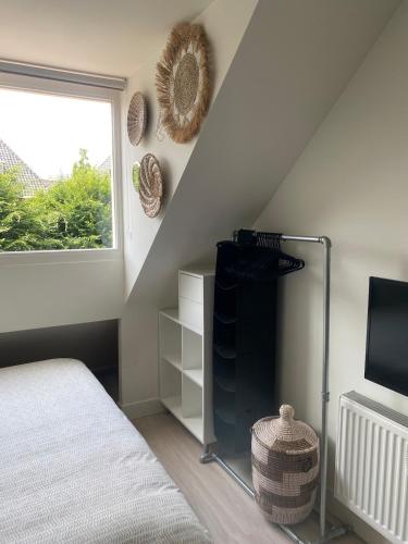 a bedroom with a bed and a tv and a window at Appartement Buissant des Amorie! in Castricum