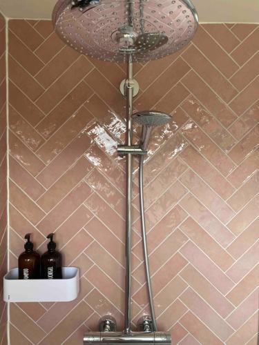 a shower head in a bathroom with brown tiles at Appartement Buissant des Amorie! in Castricum