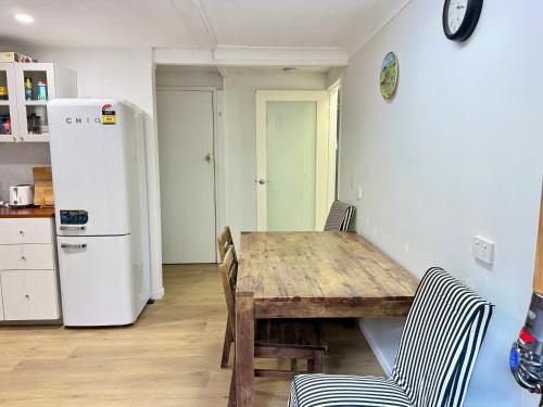 a kitchen with a wooden table and a refrigerator at Zen Escape Guest House " Location 1" - Three listings - Romantic Escape, Cozy Delight, Oasis Suite in Brisbane