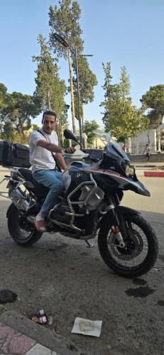 a man sitting on a motorcycle in the street at Hôtel in Bordj Bou Arreridj