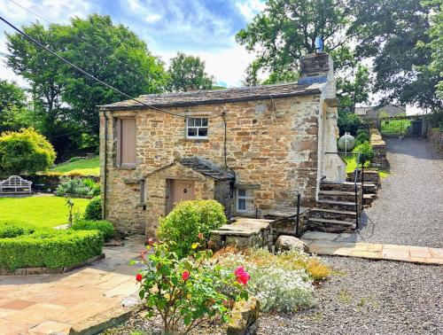 an old stone house with stairs and flowers at Beebole Cottage in Askrigg