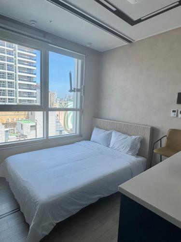 a bedroom with a white bed and a large window at 더베이먼트레지던스 in Busan