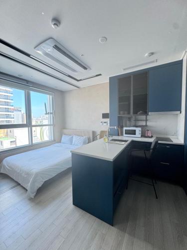a bedroom with a bed and a kitchen with a microwave at 더베이먼트레지던스 in Busan