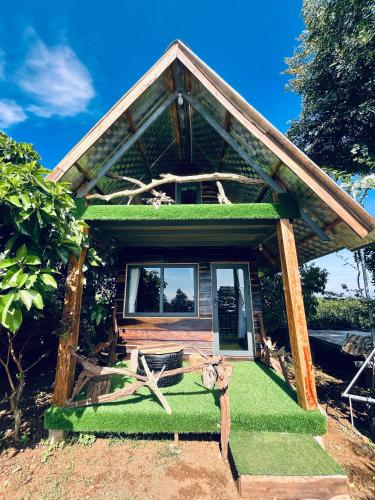 a small house with a green roof and a bench at Gia Huan Homestay - Tà Đùng in Biđong