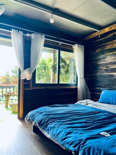 a bedroom with a bed with blue sheets and a window at Gia Huan Homestay - Tà Đùng in Biđong