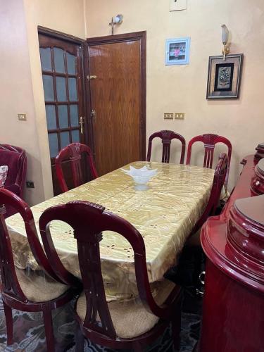 a dining room table with red chairs around it at Velvet Rose Apartment in Luxor