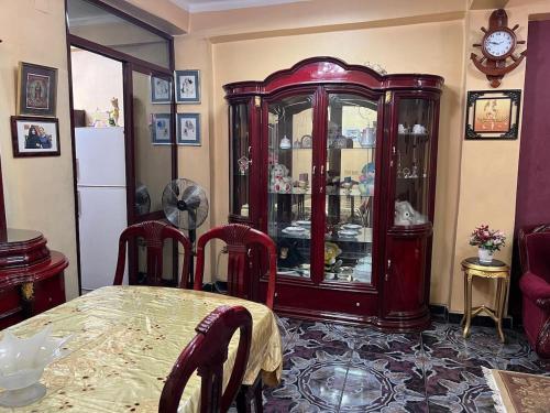 a dining room with a table and a china cabinet at Velvet Rose Apartment in Luxor