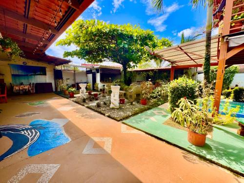 a patio with plants and trees and a building at Villas Ela en Bahía Ballena,Uvita Hermosas habitaciones privadas grandes, piscina, cocina, jacuzzi, aire acondicionado, tv y baño privado in Uvita