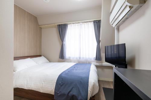 a bedroom with a bed and a flat screen tv at Sleep Inn Gotanda in Tokyo