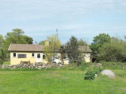 a small yellow house with a stone wall in a field at 4 person holiday home in Allinge-By Traum in Allinge