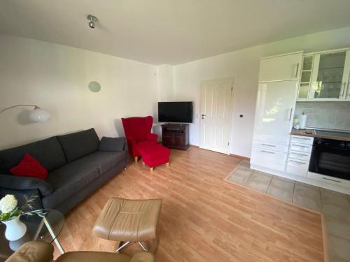 a living room with a couch and a red chair at Ruhige, gemütliche Ferienwohnung in Herzen der Lüneburger Heide in Kirchgellersen