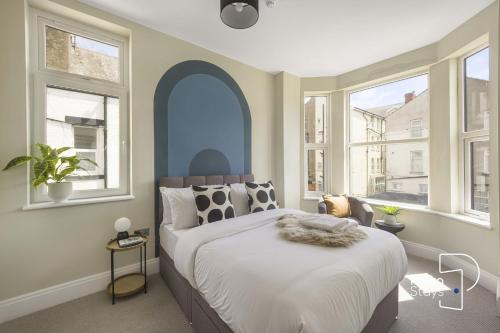 a bedroom with a large bed and windows at Luxe Ami Beh Large Group Apartment by PolkaStays in Blackpool