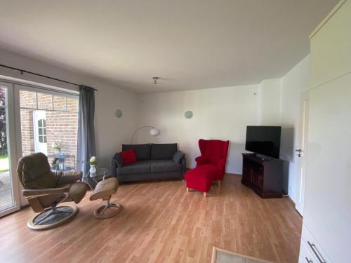 a living room with a couch and a red chair at Ruhige, gemütliche Ferienwohnung in Herzen der Lüneburger Heide in Kirchgellersen
