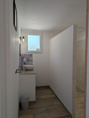 a white bathroom with a sink and a window at Cabanon La Ruine in Draguignan