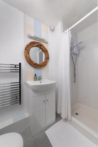 a bathroom with a sink and a shower and a mirror at Rwts Rooms & Resto in Broad Haven