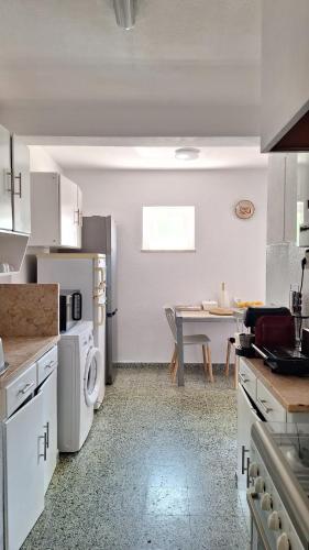 a white kitchen with a table and a dining room at Pescadores GuestHouse in Costa da Caparica