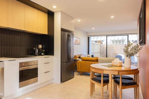 a kitchen and living room with a table and a refrigerator at CBD 2 Bed 2 Bath Luxury Gem With Free Car Park in Christchurch