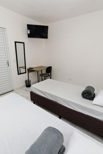 a bedroom with two beds and a table with a chair at Casa Ecotrips Barra Funda - Hostel in Sao Paulo