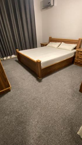 a bed in a room with a wooden frame at aljumirah furnished appartments الجميرا للشقق المفروشة in Az Zarqa