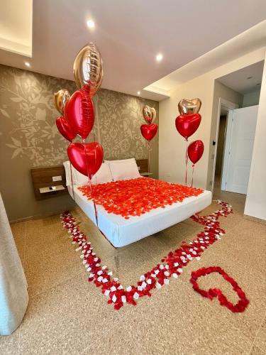 a bed with red hearts and balloons on the floor at MIRARI Design Rooms in Cala Gonone