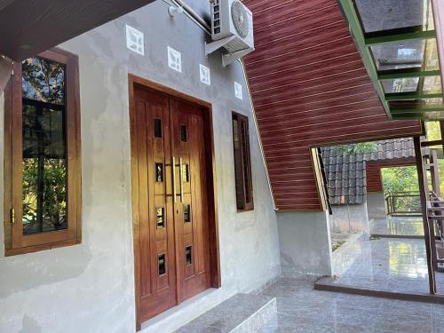 ein Haus mit zwei Holztüren und einer Veranda in der Unterkunft Villa Airunika in Bandar Lampung