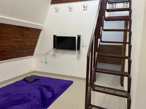ein Wohnzimmer mit einer Leiter und einem TV in der Unterkunft Villa Airunika in Bandar Lampung