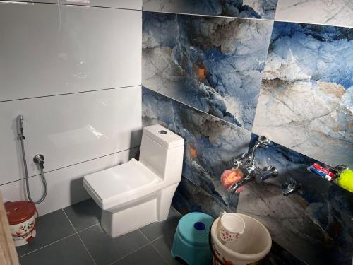 a bathroom with a white toilet and a marble wall at Siri Kuteera Homestay in Chikmagalūr