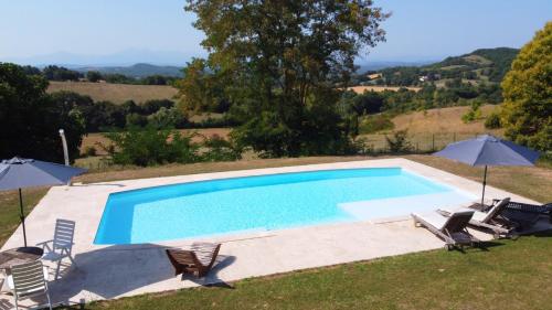 a swimming pool with two chairs and two umbrellas at Boutiquezimmer Duchesse in Mirepoix