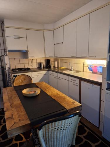 a kitchen with a wooden table and white cabinets at B&B de Vrijheid en de Ruimte in Steenbergen in Steenbergen
