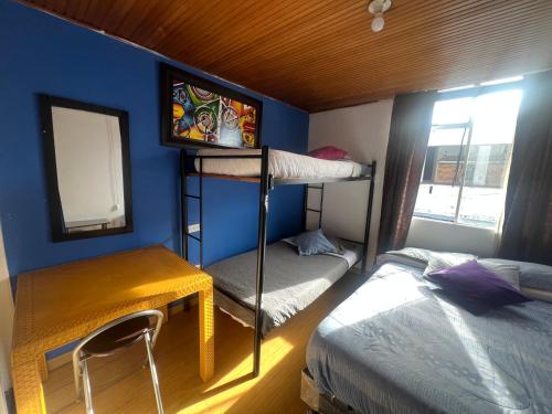 a room with two bunk beds and a desk and a bed at Habitaciones cerca a Universidad del Bosque in Bogotá
