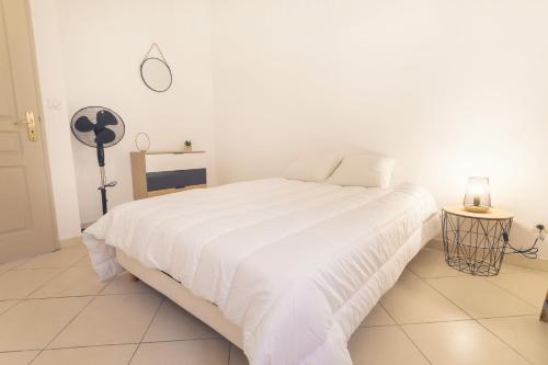 - une chambre blanche avec un grand lit blanc et un ventilateur dans l'établissement Appartement tout équipé 4 à 6 couchages au cœur de Beziers, à Béziers