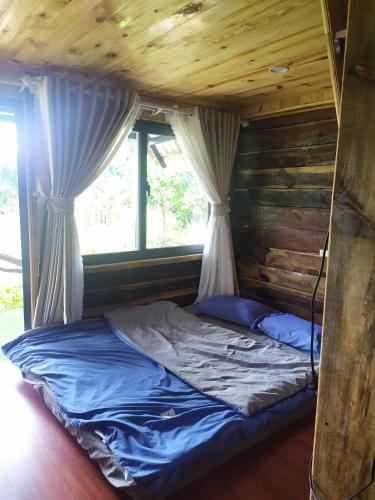 a bed in a log cabin with curtains at Gia Huan Homestay - Tà Đùng in Biđong