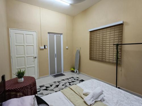 a room with a bed and a window and a door at GreenAcres Cottage in Pasir Puteh