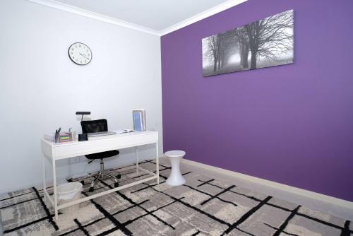 a room with a desk and a purple wall at Homely Retreat-4 Minutes from Pacific Werribee Shopping Centre in Werribee
