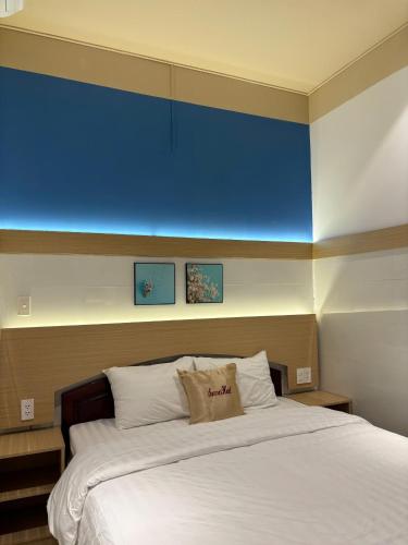 a bedroom with a large bed with a blue wall at Summer Hotel in Dĩ An