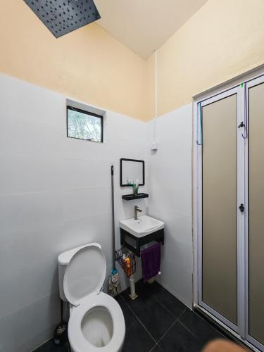a bathroom with a toilet and a sink at GreenAcres Cottage in Pasir Puteh