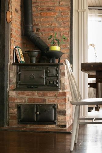 an old brick fireplace with a stove and a chair at Cozy white house close to the nature with Wi-Fi 