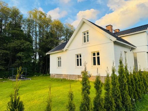 a white house with a green field and trees at Cozy white house close to the nature with Wi-Fi 