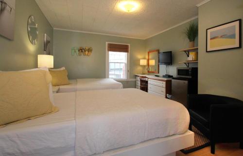 a bedroom with two beds and a desk and a television at Eagle House Motel in Rockport