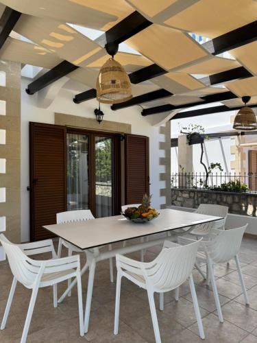 a dining room with a white table and white chairs at Le Soleil De Lindos - Luxury Villa with Swim Spa in Líndos