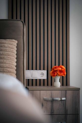 a vase of orange flowers on a dresser in a bedroom at Royal View Guest House in Dospat