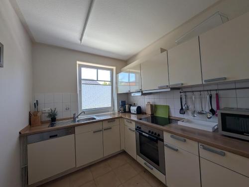 a kitchen with white cabinets and a sink and a window at Ferienwohnung in Boltenhagen in Boltenhagen