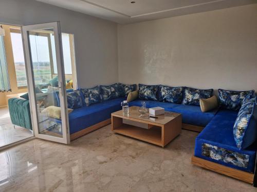 a living room with a blue couch and a table at Bel appartement pour location in O Ben Slimane