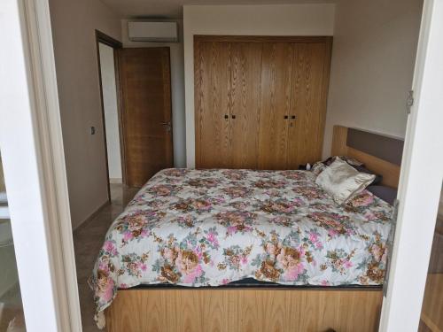 a bedroom with a bed with a floral comforter at Bel appartement pour location in O Ben Slimane