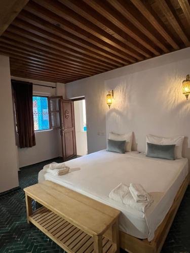 a bedroom with a large white bed with a wooden ceiling at Medina social club in Fès
